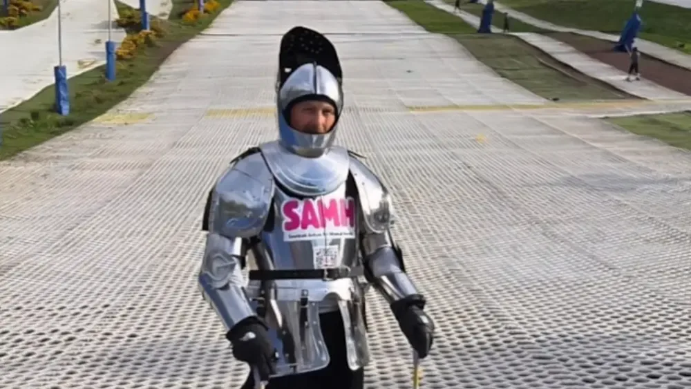 Jay Watt dressed in a full suit of armour standing on a dry ski slope