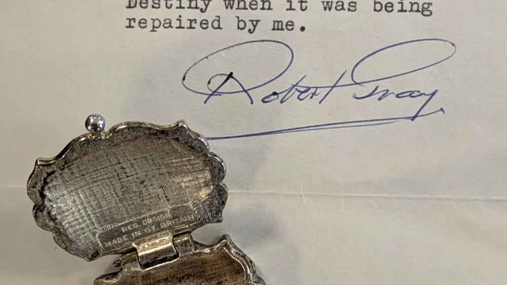 A small piece of stone lying in an ornate metal box, on top of a typed letter saying it is a piece of the Stone of Destiny
