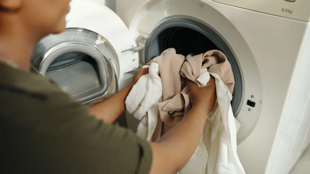 A woman loads washing into a washing machine