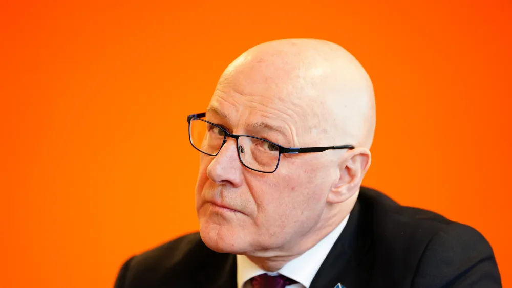John Swinney listens during a visit to Warmer Homes Scotland