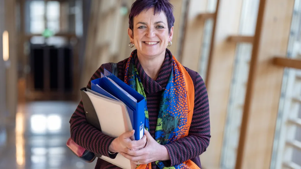 Angela Constance smiling while walking through a corridor at Holyrood