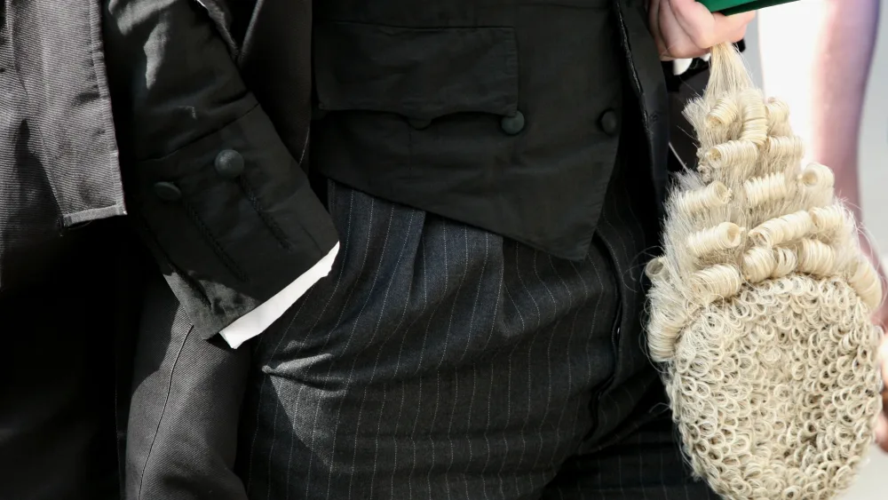 A barrister carrying their wig, walking outside