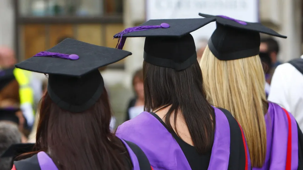 The backs of three young women in graduation gowns and hats