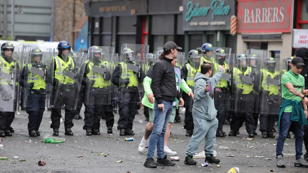 A line of police officers standing behind Celtic fans