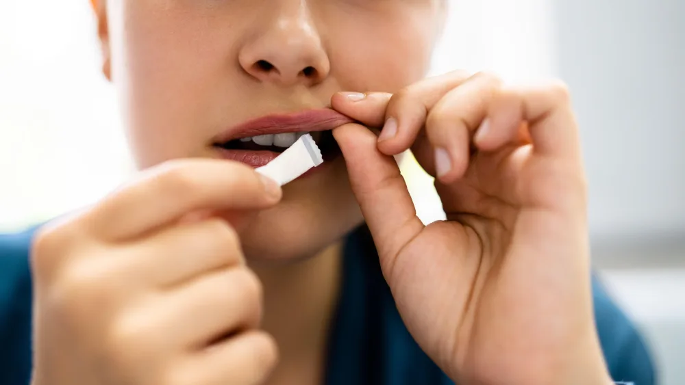 A woman putting a nicotine pouch inside her mouth