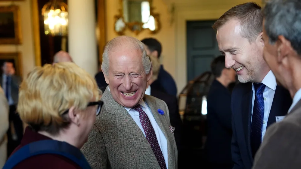 The King laughing while standing amongst a group of people