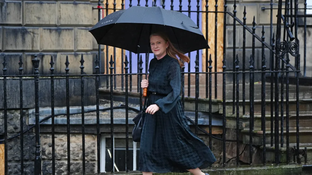 Shirley-Anne Somerville sheltering under an umbrella while walking along a street