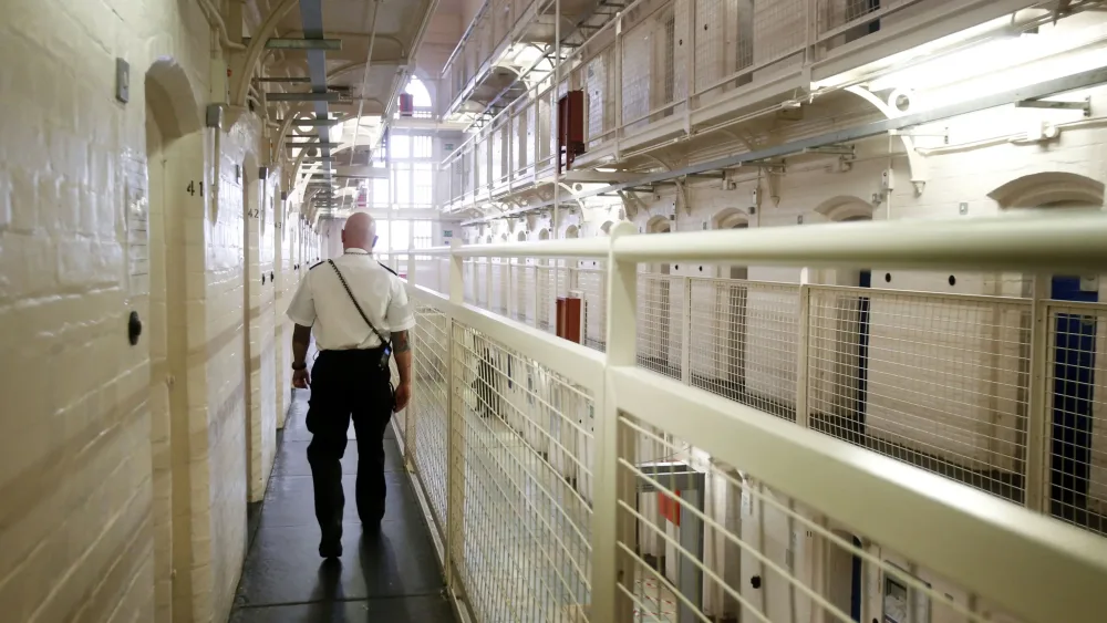A prison officer walking along a prison wing
