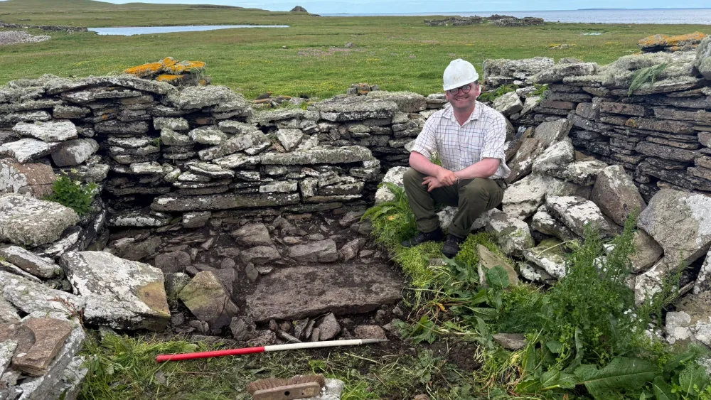 Dan McLean smiling while seated in a ruin