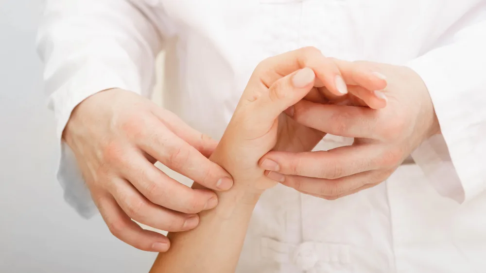 Doctor checking heart rate on wrist of woman