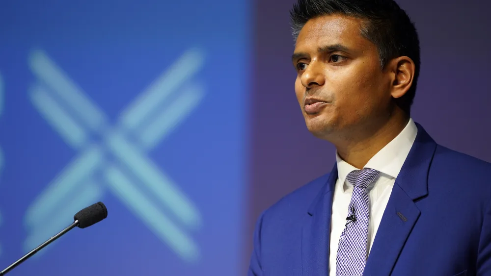 Dr Sandesh Gulhane speaking into a mic, in front of Scottish Tory signage
