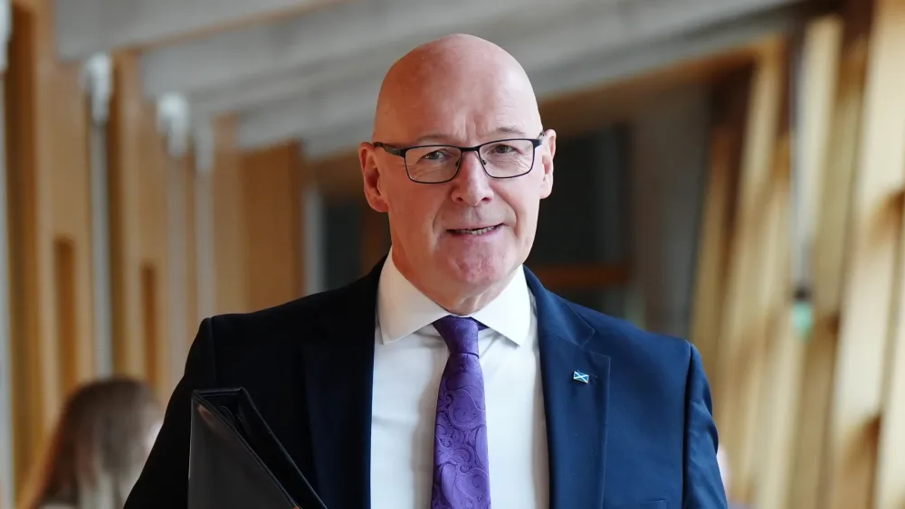 John Swinney walking through a corridor in Holyrood