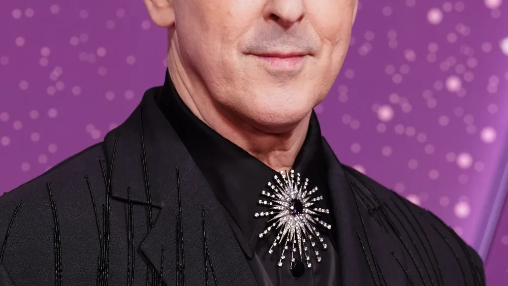 Alan Cumming in black suit on a red carpet