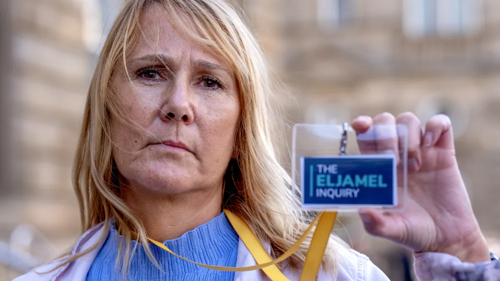 Jules Rose holding up her Eljamel Inquiry pass, standing outside