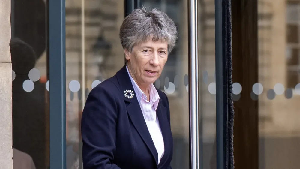 Liz Smith exiting a glass-fronted builing