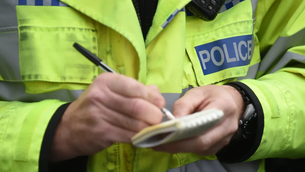 Close-up of a police officer writing on a notepad