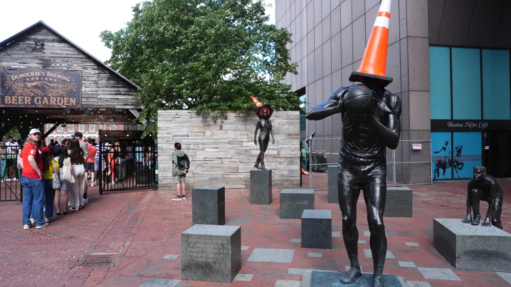 A statue of basketball player Bill Russell with a orange cone on the top of it in Boston
