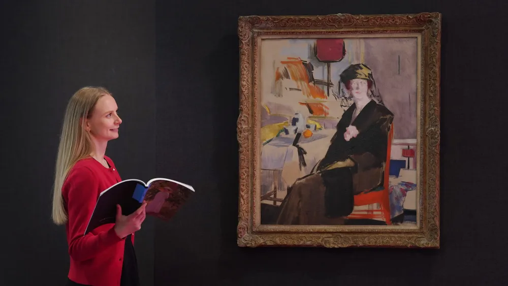 A woman standing next to and looking at the painting Interior: The Lady In Black