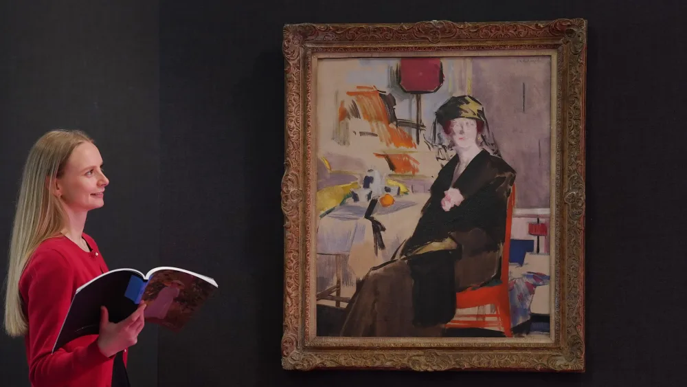 A woman smiling while looking at the FCB Cadell painting hanging on a wall