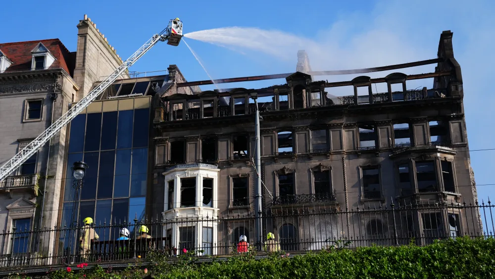 Firefighters work on a building which shows signs of extensive fire damage