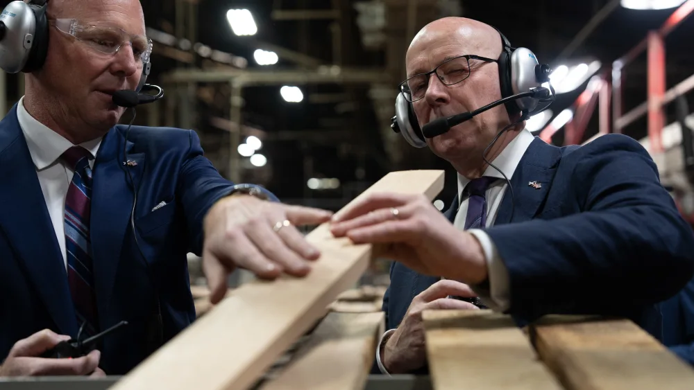 First Minister John Swinney looking at wooden planks during a tour in Kentucky.