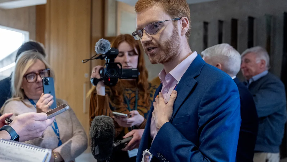 Ross Greer speaking in a media huddle at Holyrood