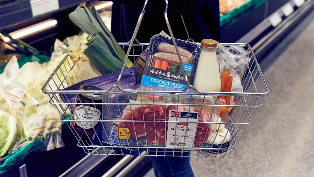 A shopper with a basket of goods in a supermarket