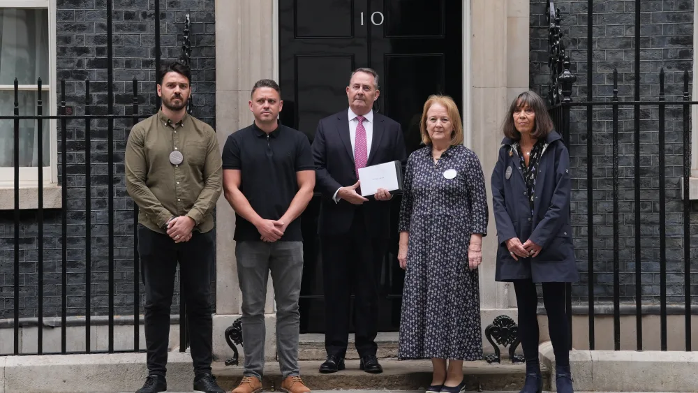 Sir Liam Fox (centre) arrives to hand in a letter to 10 Downing Street joined by some of the families affected by the Chinook helicopter crash
