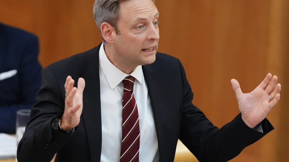 Liam Kerr gesturing with both arms while speaking in Holyrood