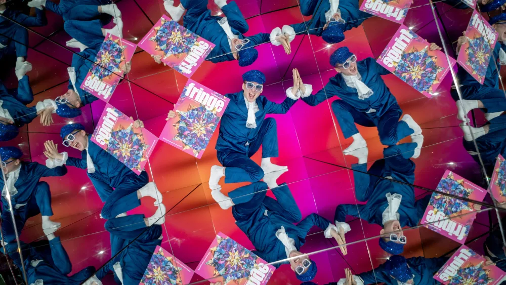 A performer holding a Fringe programme, reflected several times in giant kaleidoscope