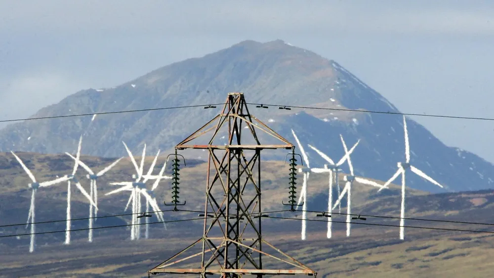 Electricity pylons and wind turbines, with a mountain in the background