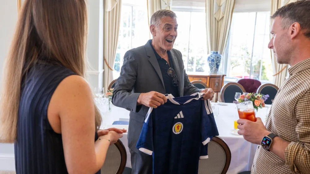 George Clooney smiles as he receives a Scotland football kit