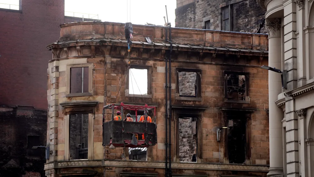 Workmen in an aerial basket inspect the remains of a fire-damaged building