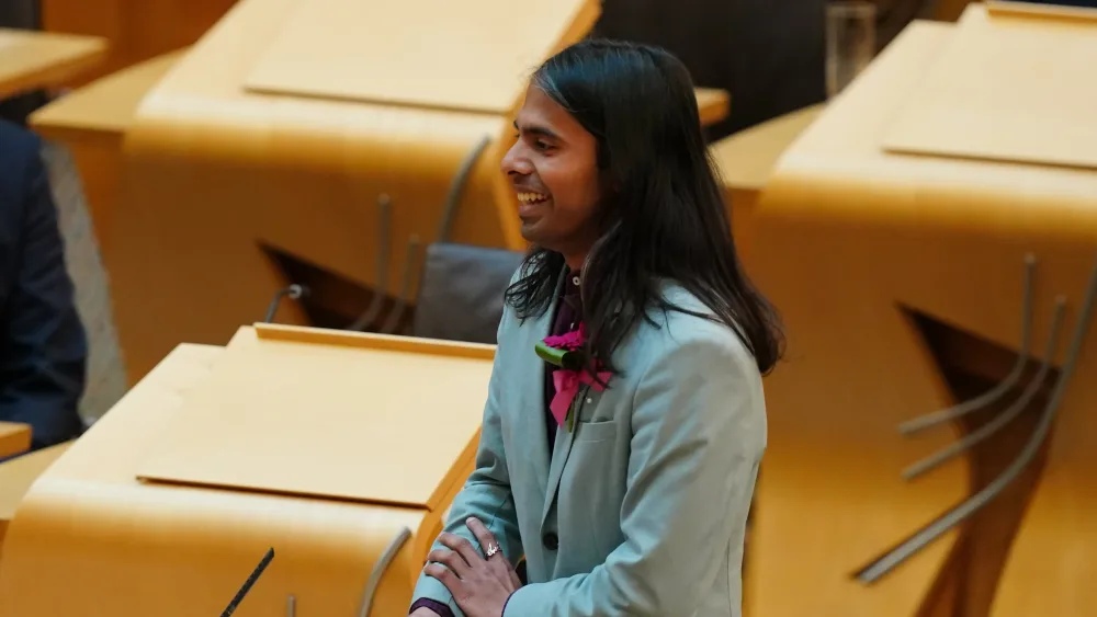 Side view of Q Manivannan standing in the main Holyrood chamber
