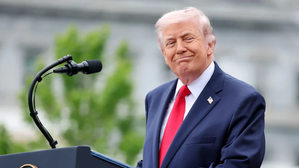 Donald Trump smiling while standing at a lectern outside