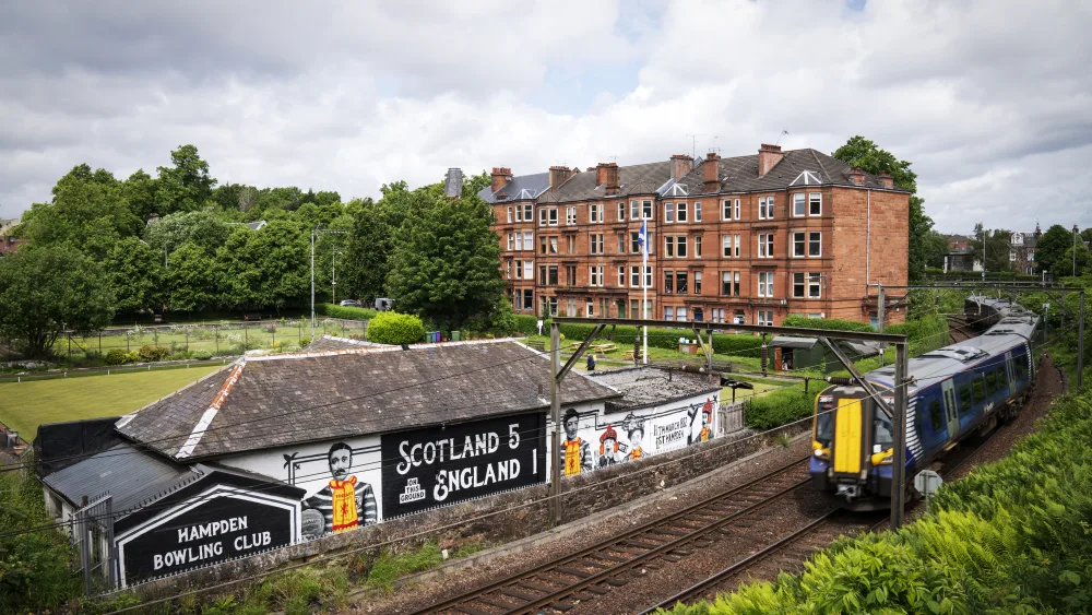 A train passing by a mural which says Scotland 5 England 1