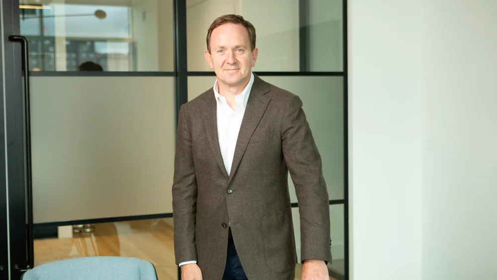 Handout photo of Malcolm Robertson smiling, while standing in an office
