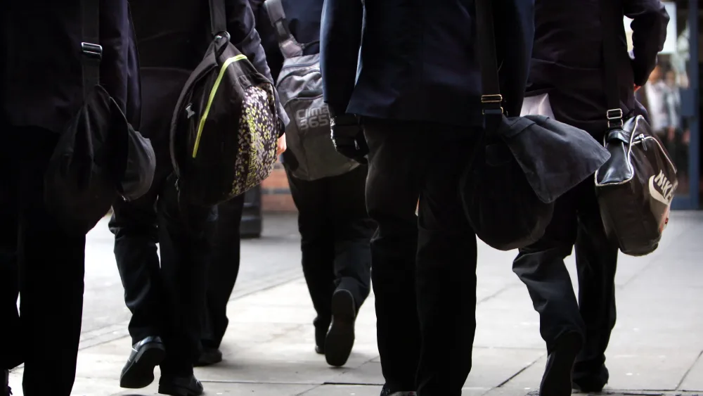 Secondary school pupils in uniform, walking down a street