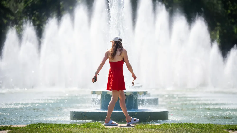 A woman by a fountain in the sun