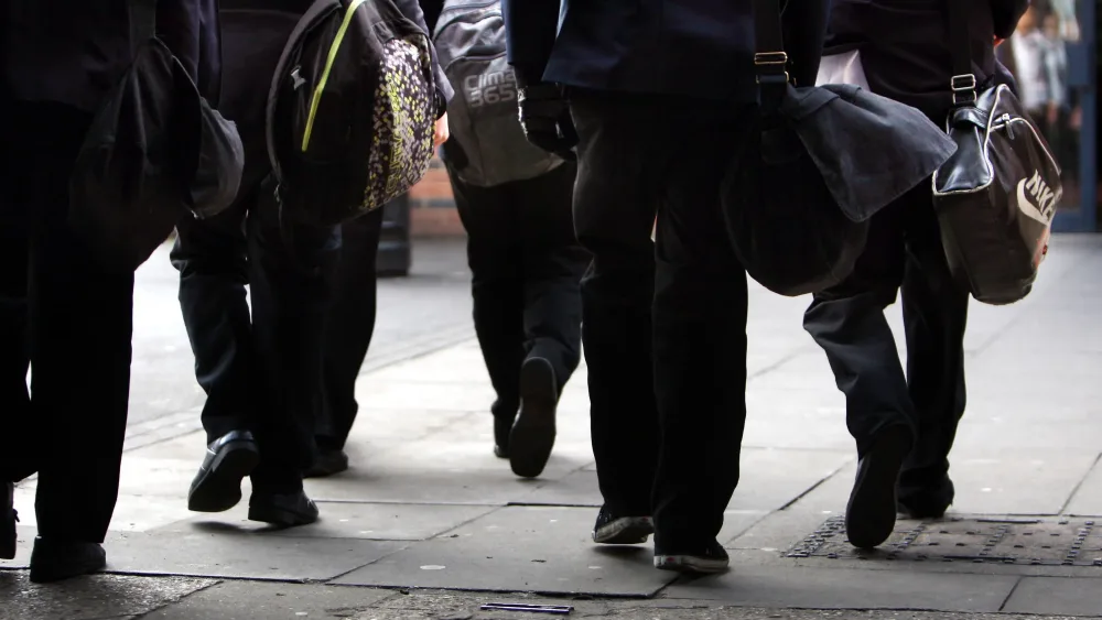 The legs of senior school pupils walking along a street
