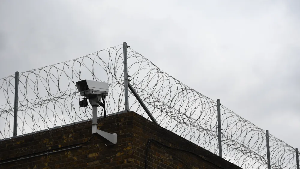 A view of a high wall, topped with barbed wire
