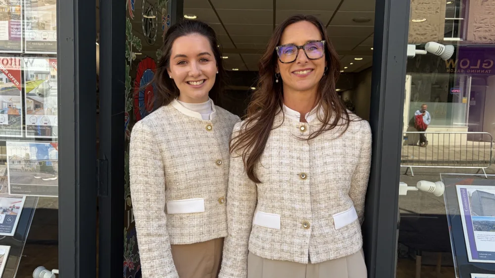 Jodi Gregg and Julie Gallagher smiling at the door of an estate agent shop