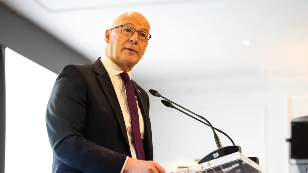 John Swinney standing next to a microphone