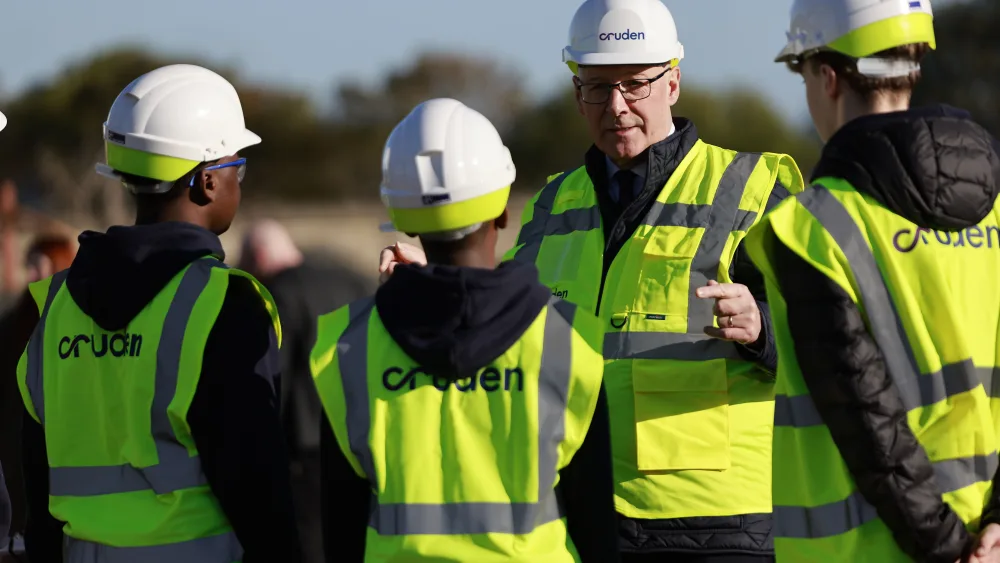 John Swinney chatting to three people, with them all wearing hard hats and hi-viz vests