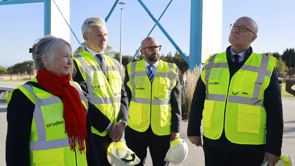 John Swinney standing outside in a group of four, with them all wearing using hard hats and hi-viz vests
