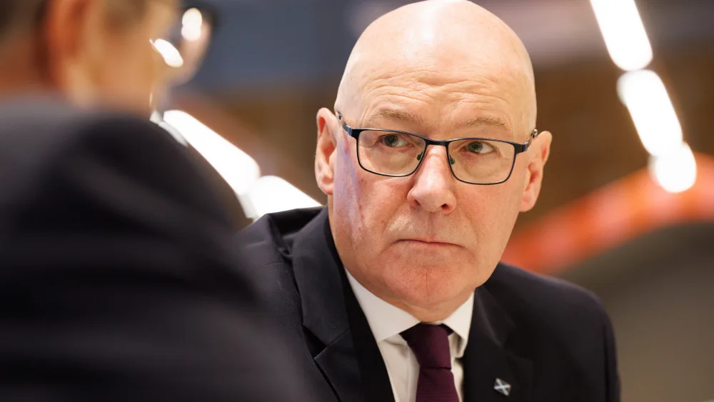 John Swinney listens to a speaker during a visit to a health hub