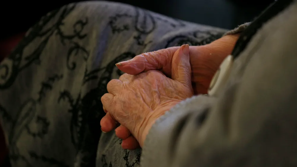 The hands of an elderly woman clasped in her lap