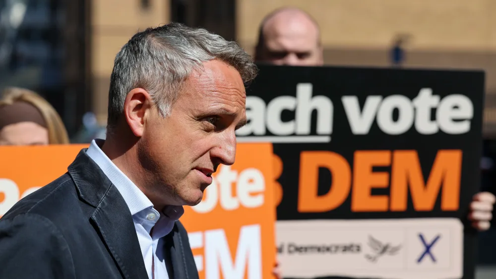 Alex Cole-Hamilton looking serious in front of some Lib Dem placards