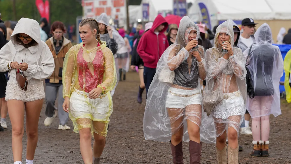 Festivalgoers shelter from the rain in plastic ponchos as they walk through the muddy site at the Reading Festival at Little John’s Farm, Reading, Berkshire
