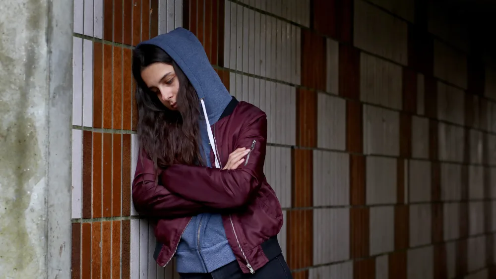 A distressed looking teenager in an underpass